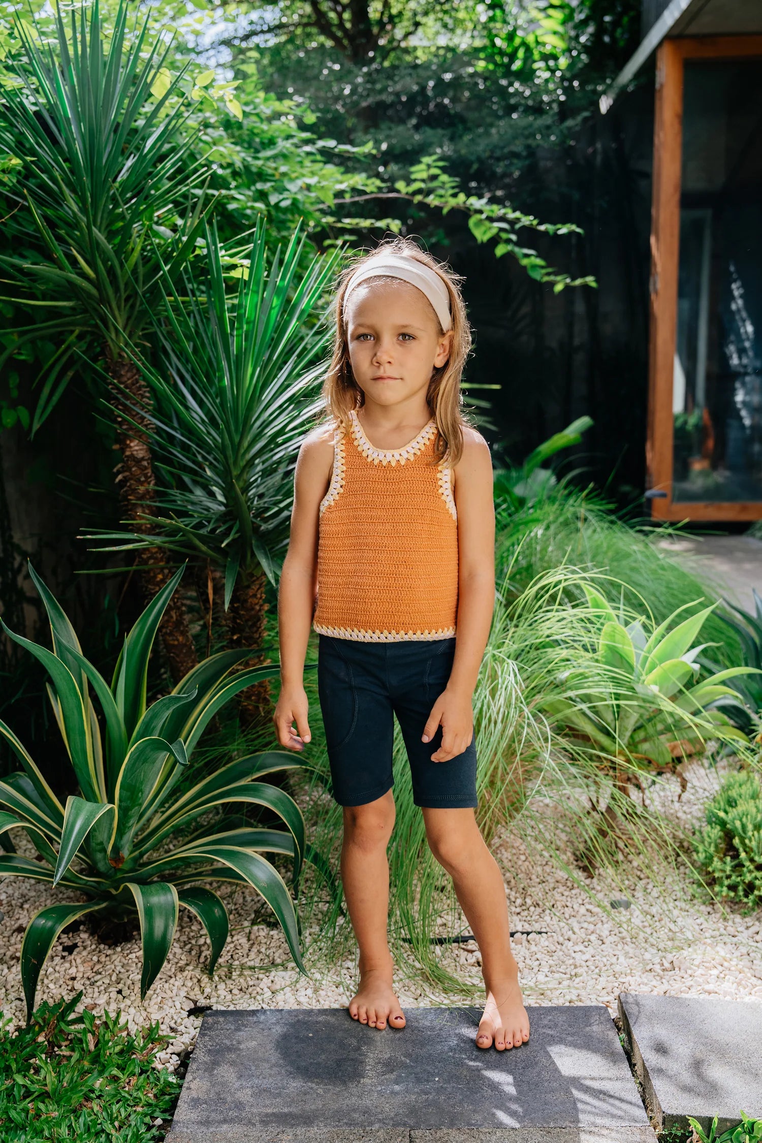 Kids standing in front of greenery wearing crochet and cotton outfits